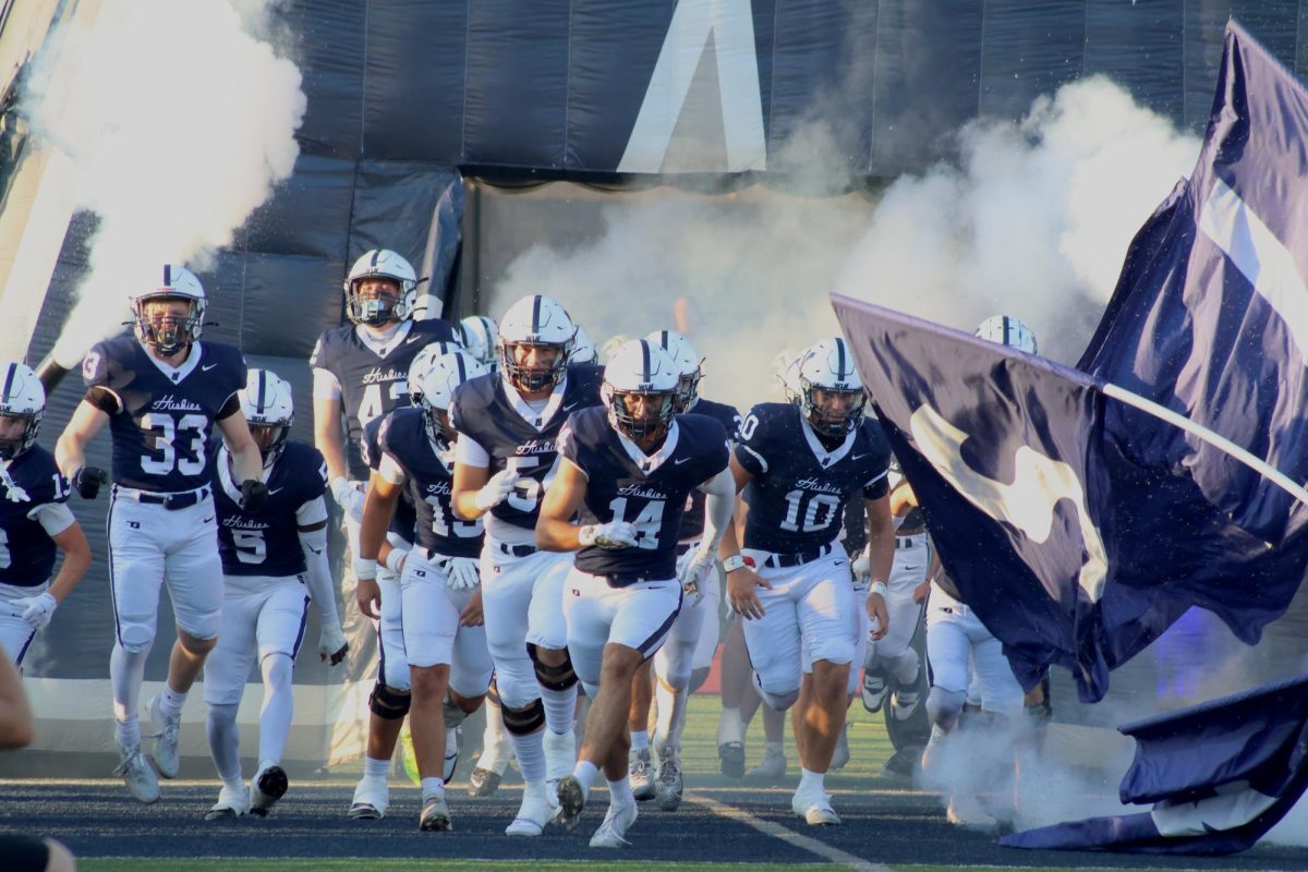 Husky team running onto the field together.