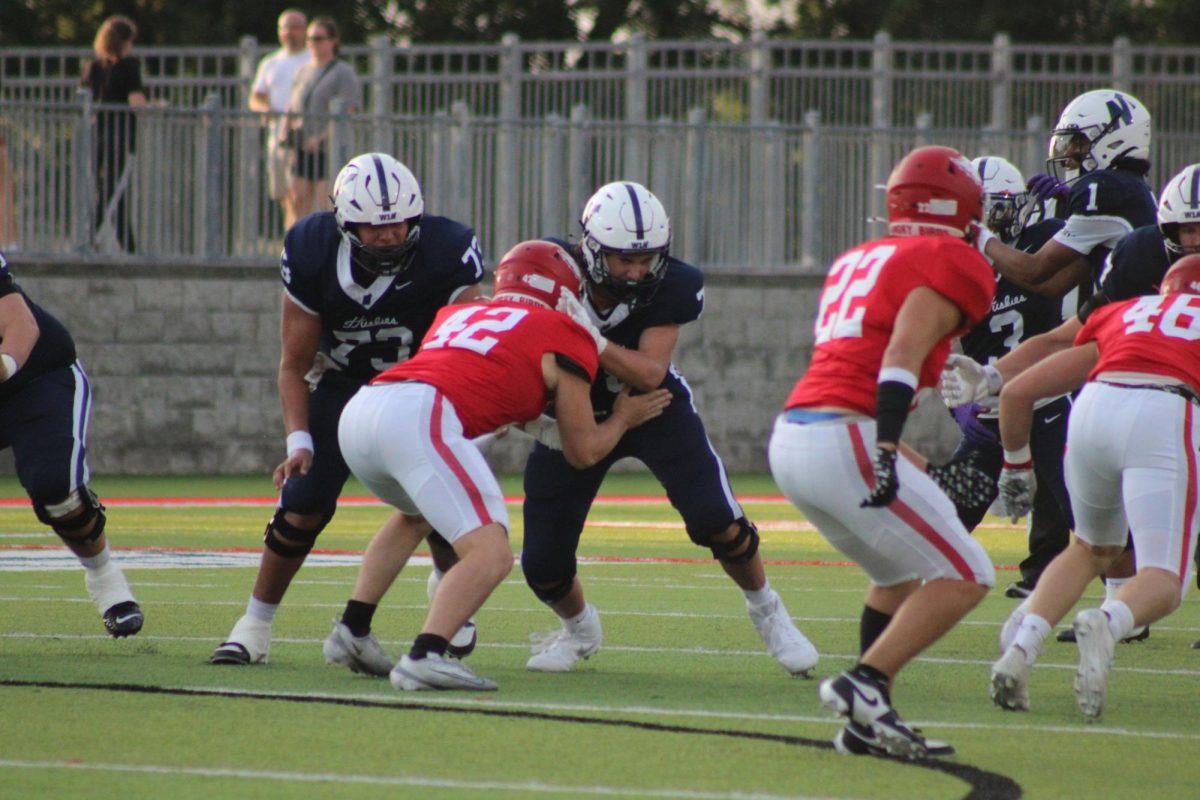Husky offensive line blocking against Farmington Cardinals defensive line.